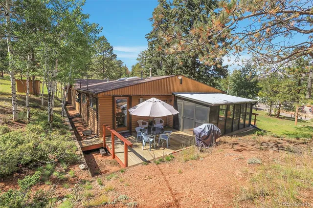 a view of a wooden house with a yard and sitting area