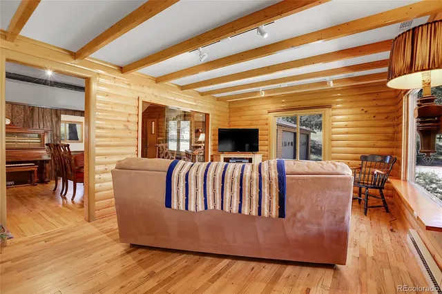 a living room with furniture kitchen view and a wooden floor