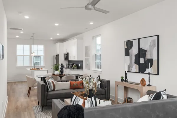 a living room with furniture kitchen view and a large window