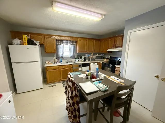 a kitchen with a refrigerator a stove a sink dishwasher with a dining table and chairs