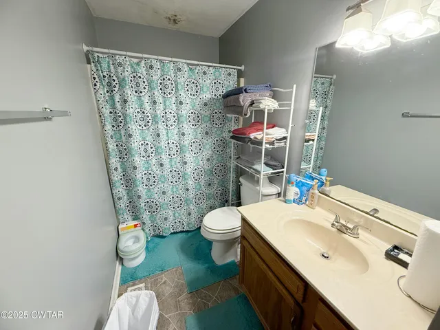 a bathroom with a sink a toilet and shower curtain