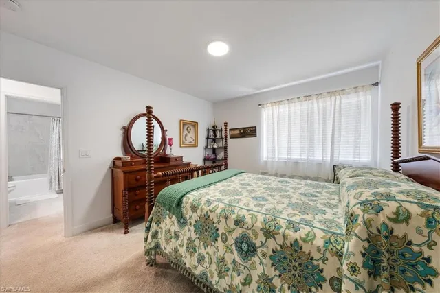 a bed sitting in a spacious bedroom next to a window and dresser