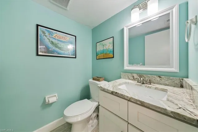a bathroom with a granite countertop toilet a sink and mirror