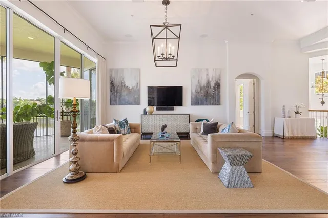 a living room with furniture a flat screen tv and a floor to ceiling window