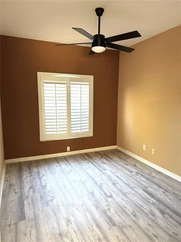 a view of an empty room with a window and wooden floor