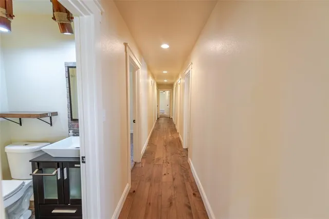 a view of a hallway with wooden floor and a bathroom