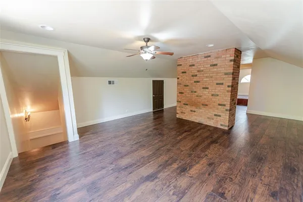 an empty room with wooden floor chandelier fan and windows