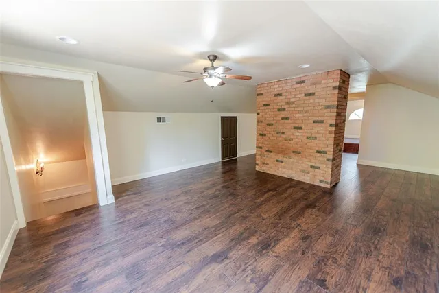 an empty room with wooden floor chandelier fan and windows