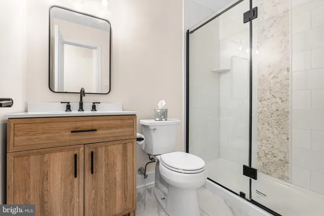 a bathroom with a toilet sink vanity and shower