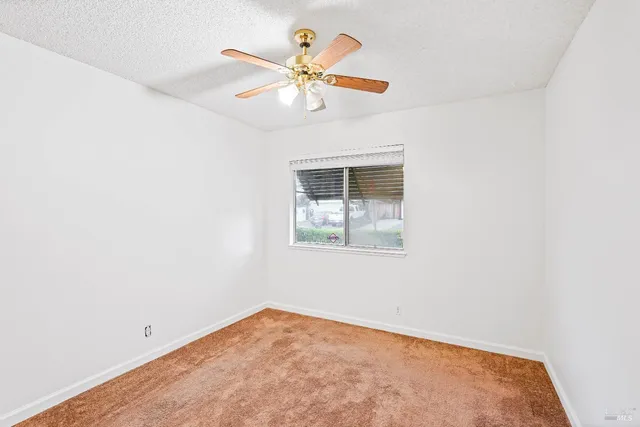 an empty room with a window and a fan