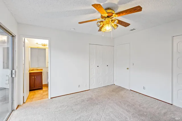 an empty room with closet and a chandelier fan