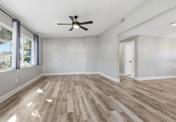 a view of empty room with wooden floor and fan