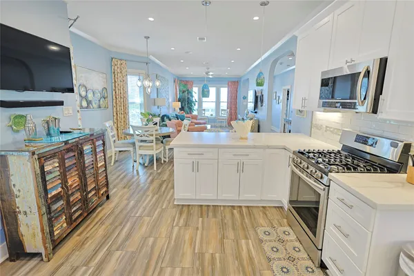 a kitchen with stainless steel appliances a stove top oven a sink dishwasher a dining table and chairs with wooden floor