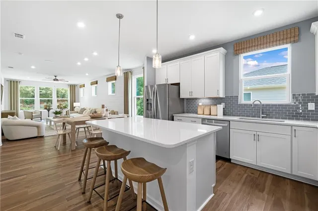 a kitchen with a sink a stove a refrigerator and white cabinets with wooden floor