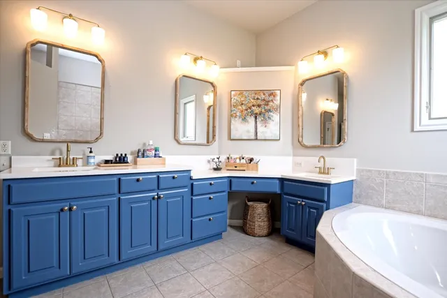 a bathroom with a tub a sink double vanity and mirror