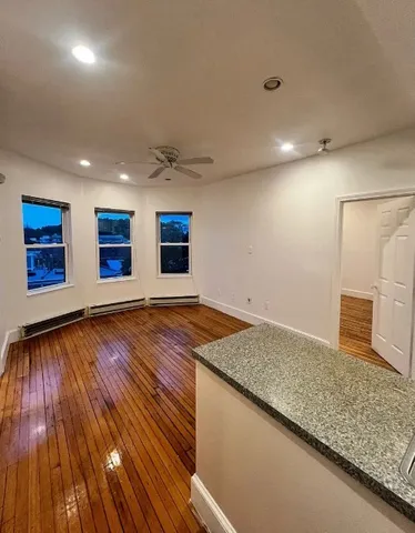a view of an empty room with wooden floor and window