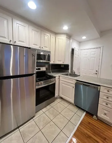 a kitchen with granite countertop a refrigerator sink and cabinets