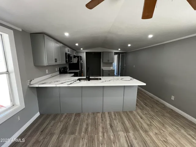 a kitchen with kitchen island granite countertop a sink counter top space appliances and cabinets