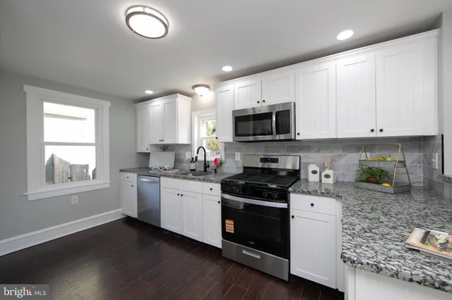 a kitchen with granite countertop white cabinets and appliances