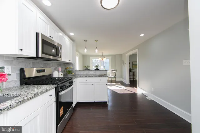 a kitchen with granite countertop wooden cabinets stainless steel appliances and a sink