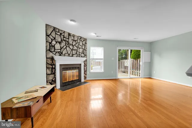 a view of an empty room with wooden floor fireplace and a window
