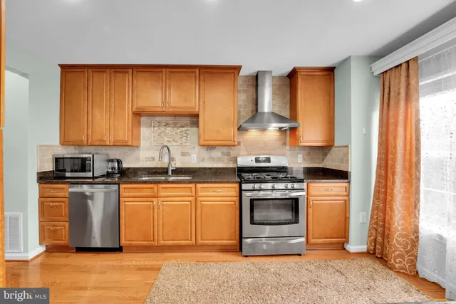 a kitchen with stainless steel appliances granite countertop a stove a sink and a refrigerator