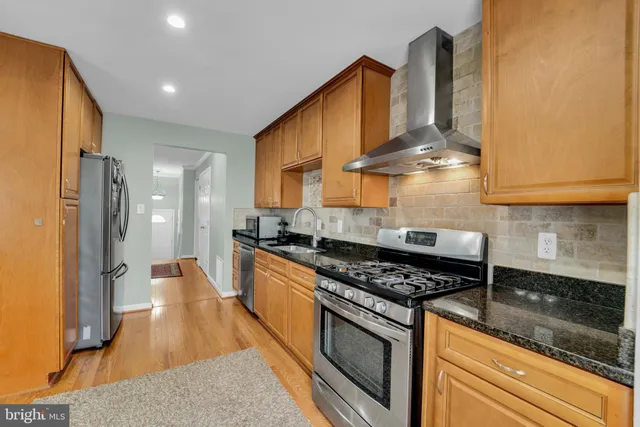 a kitchen with stainless steel appliances granite countertop a sink stove and refrigerator