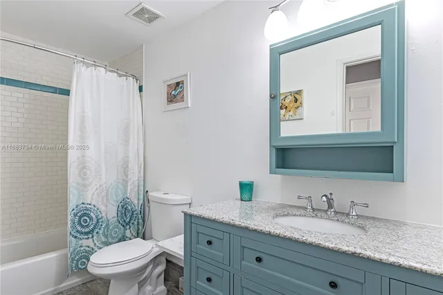 a bathroom with a granite countertop sink a toilet and a mirror