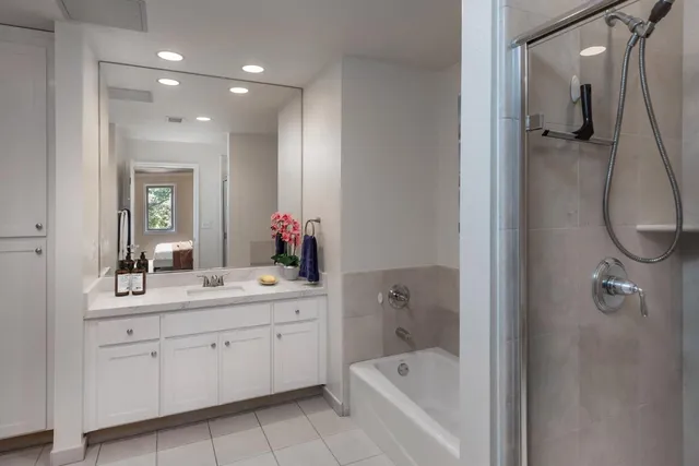 a bathroom with a tub sink a mirror a vanity and a shower
