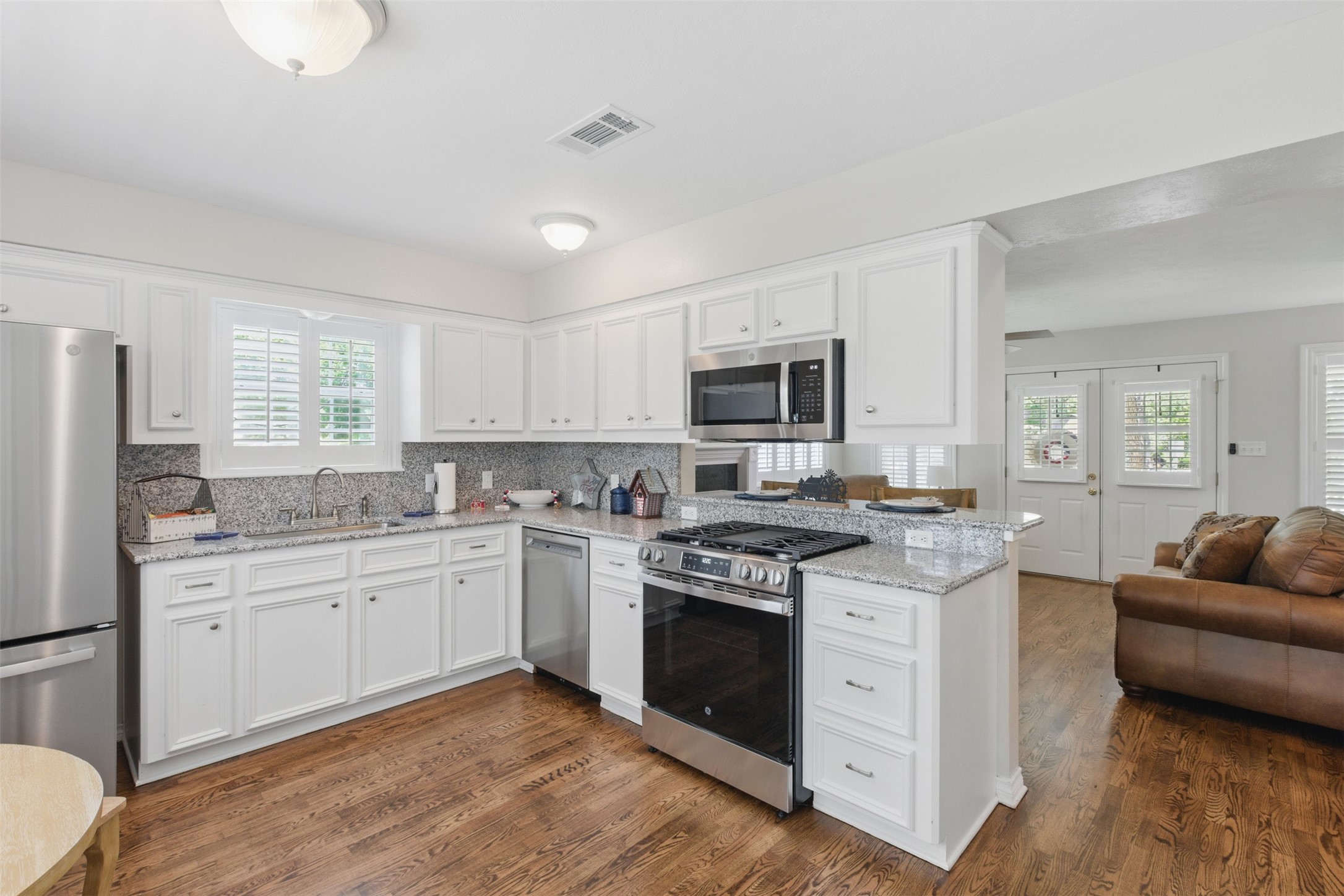 407 West Main Street Brenham, TX 77833 - Photo 15 of 50 a kitchen with stainless steel appliances granite countertop a stove top oven a sink dishwasher a refrigerator and white cabinets with wooden floor