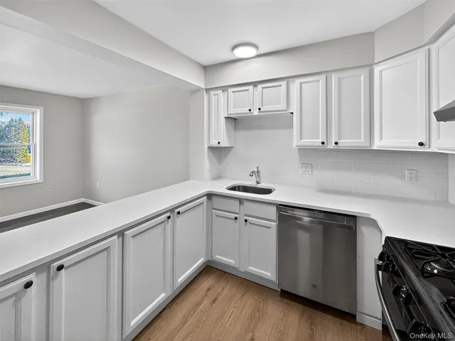 a kitchen with a sink dishwasher and white cabinets with wooden floor