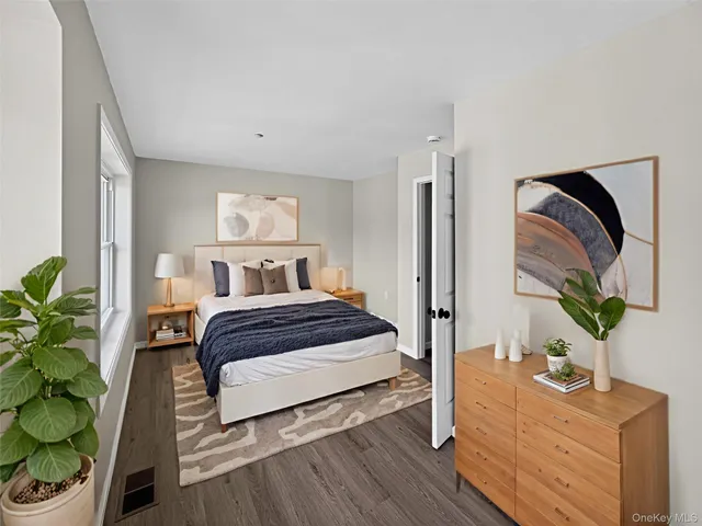 a bedroom with a bed potted plants on the dresser and next to a window