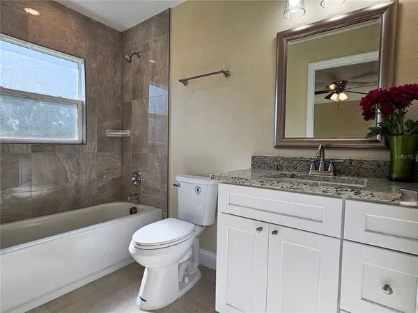 a bathroom with a granite countertop toilet a sink and a bathtub