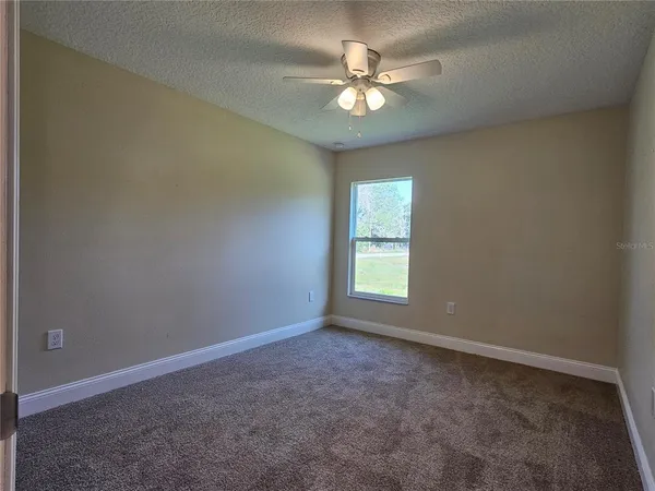 an empty room with a chandelier fan and windows