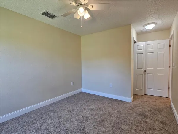 an empty room with a chandelier fan and closet