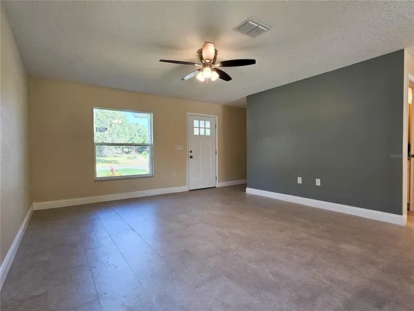 an empty room with fan and windows