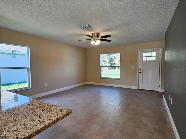 an empty room with windows and ceiling fan