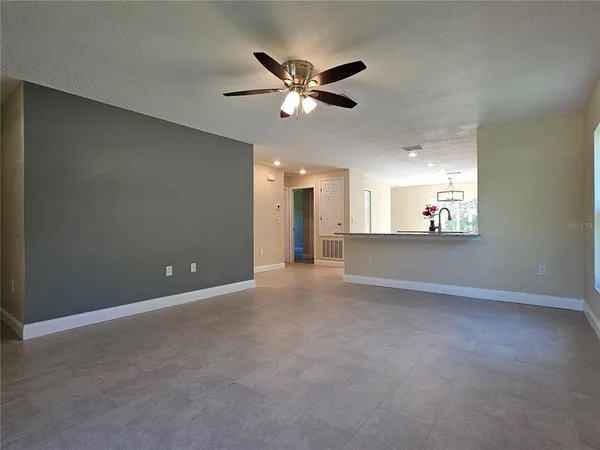 a view of an empty room with a ceiling fan and window