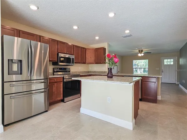 a kitchen with kitchen island granite countertop stainless steel appliances and refrigerator