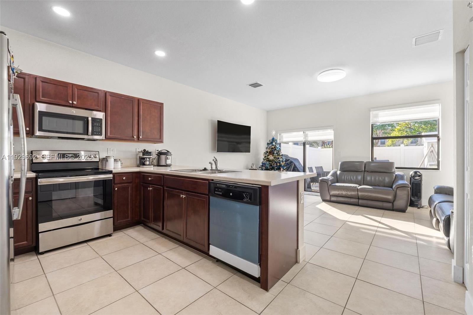 3272 West 92nd Place Hialeah, FL 33018 - Photo 7 of 37 a kitchen with stainless steel appliances granite countertop a stove top oven a sink dishwasher a dining table and chairs with wooden floor