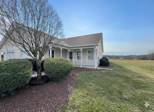 a front view of a house with garden and trees
