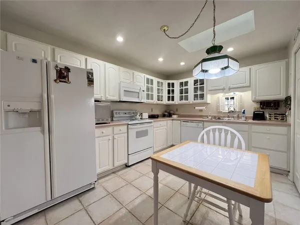 a kitchen with kitchen island granite countertop a sink a counter space appliances and cabinets