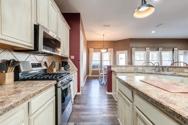 a kitchen with granite countertop kitchen island stainless steel appliances a sink and living room view