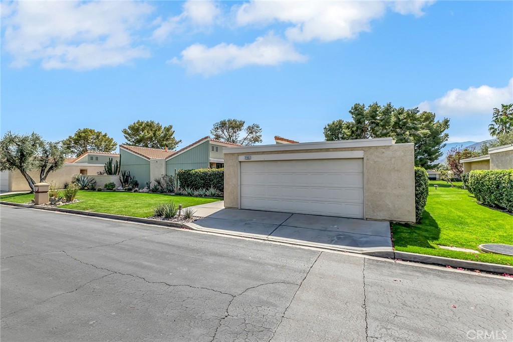 72355 Roxbury Drive Rancho Mirage, CA 92270 - Photo 10 of 61 a view of a white house with a small yard and a large parking space