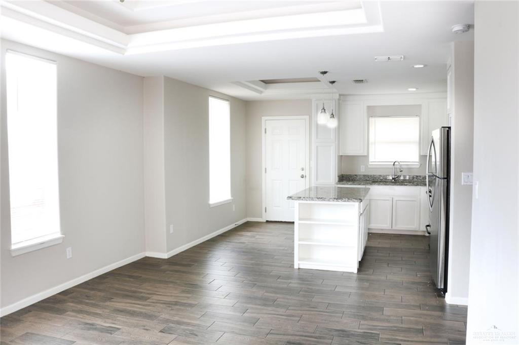 701 Cathedral Hill, Unit 1 Edinburg, TX 78541 - Photo 3 of 14 Kitchen with a tray ceiling, open shelves, light stone countertops, white cabinets, and a center island