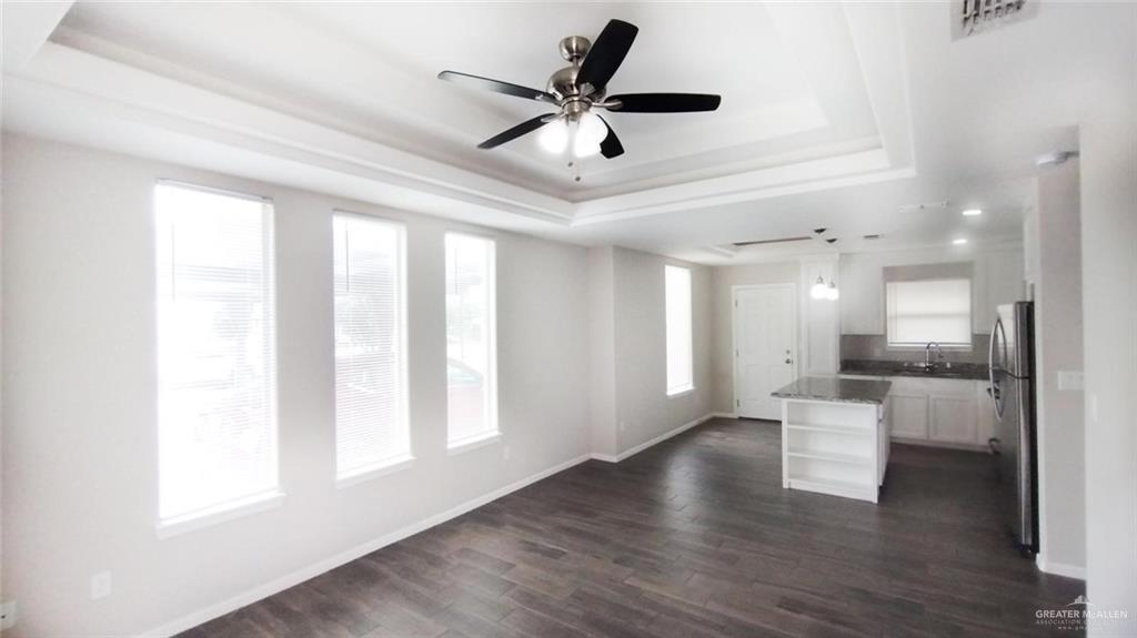 701 Cathedral Hill, Unit 1 Edinburg, TX 78541 - Photo 4 of 14 Unfurnished living room featuring a tray ceiling, dark wood-type flooring, healthy amount of natural light, and a ceiling fan