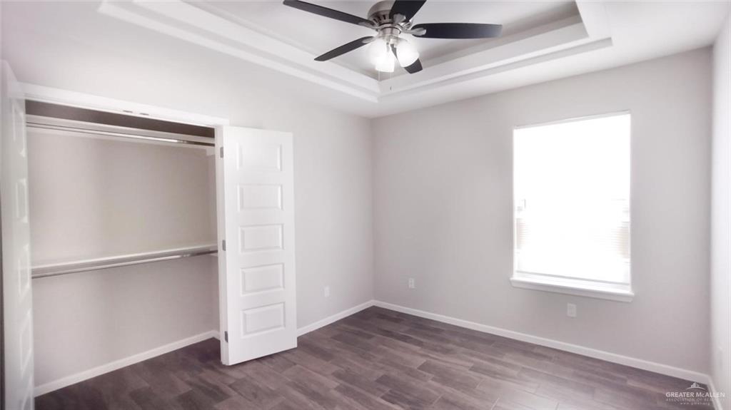 701 Cathedral Hill, Unit 1 Edinburg, TX 78541 - Photo 7 of 14 Unfurnished bedroom with dark wood finished floors, a closet, a tray ceiling, and a ceiling fan