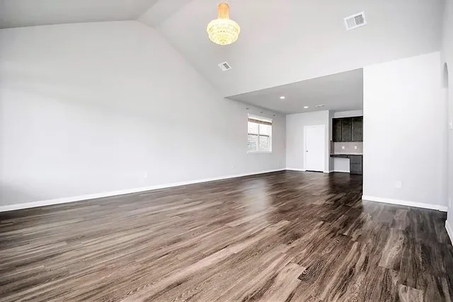 a view of an empty room with window and wooden floor