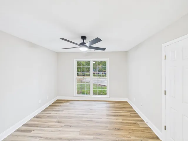 a view of an empty room with wooden floor and a window