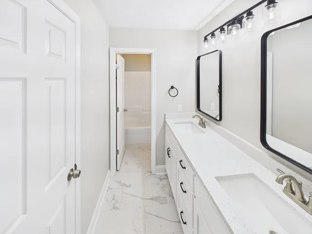 a spacious bathroom with a double vanity sink mirror and shower